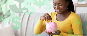 Woman smiling while putting change into a piggy bank