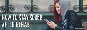 Picture of a red-headed girl smiling while looking at her phone, wearing a hoody that reads, How to Stay Sober After Rehab